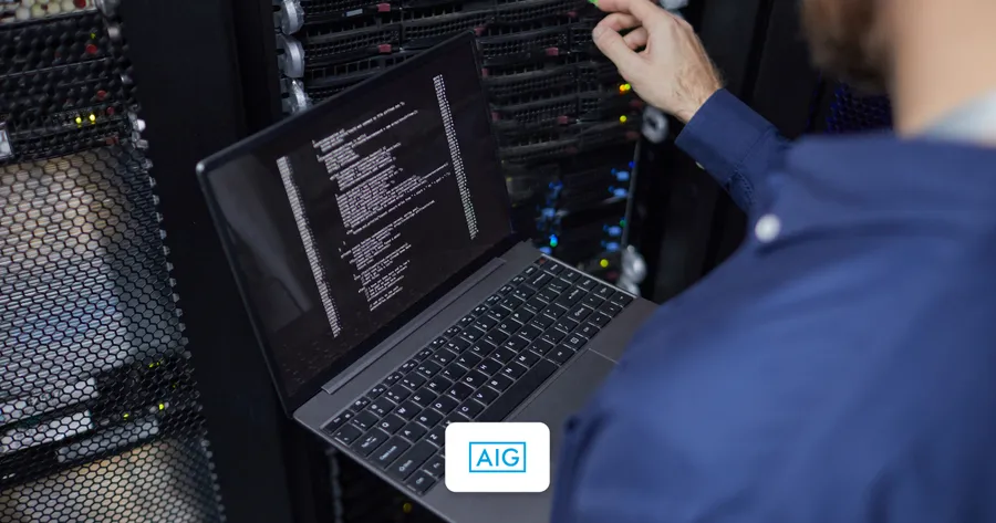 Τεχνικός με laptop μπροστά σε rack data center, μπλε στολή — AIG Cyber Insurance